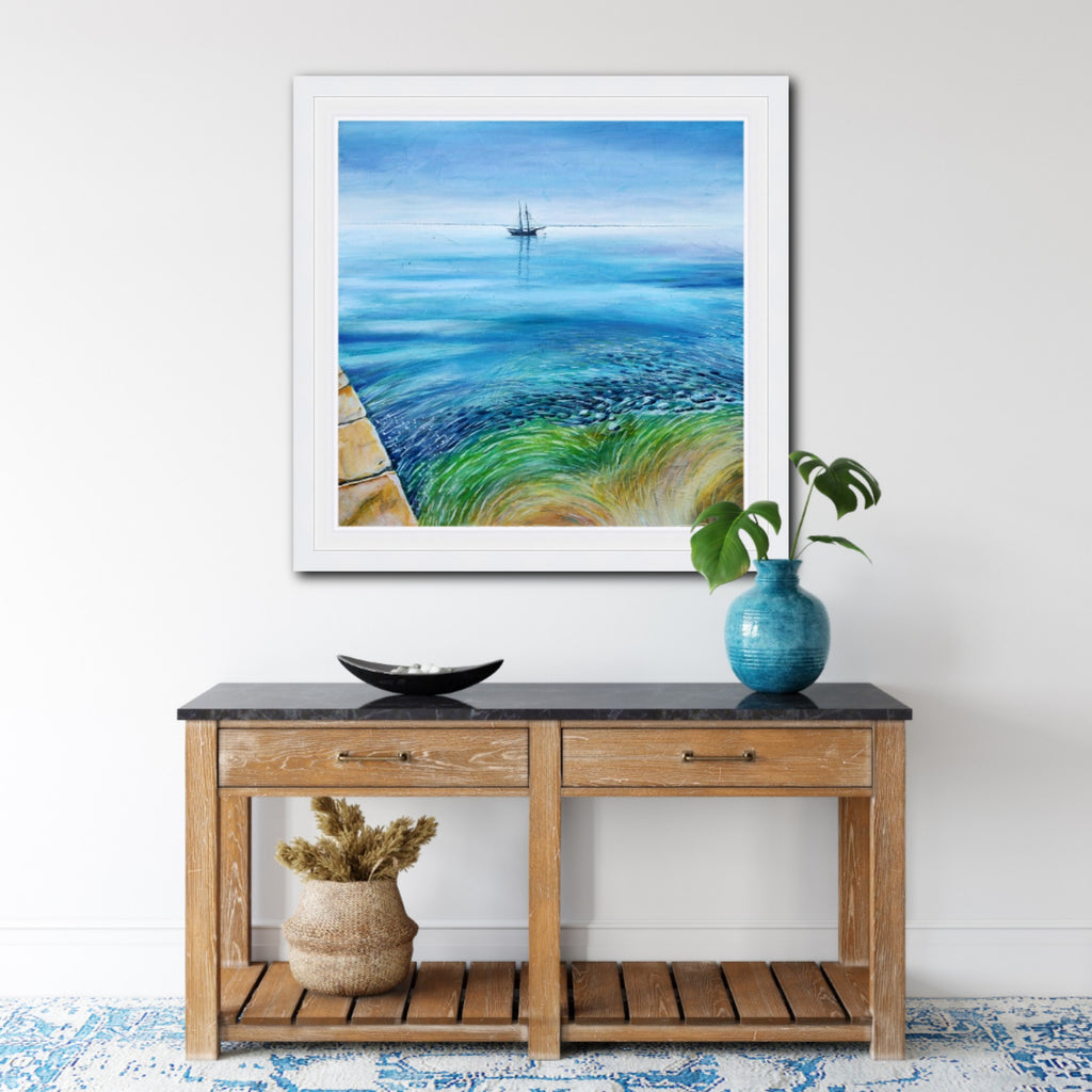 original painting of a tall ship in St. Austell Bay, Cornwall by Liz Hackney, shown hanging on a wall above a sideboard.