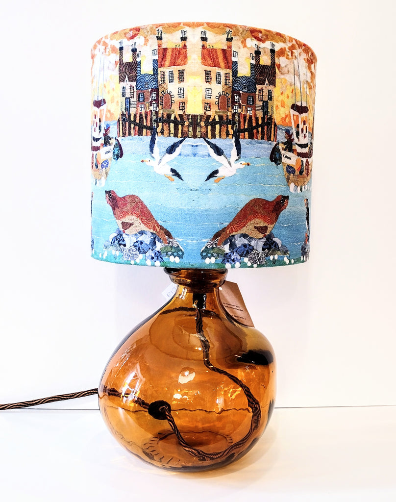 Amber coloured glass lamp-base shown with a coastal lampshade